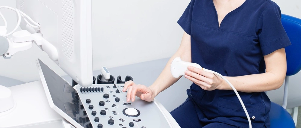 Female doctor woman in uniform sitting in office in a hospital with ultrasound diagnostic machine equipment