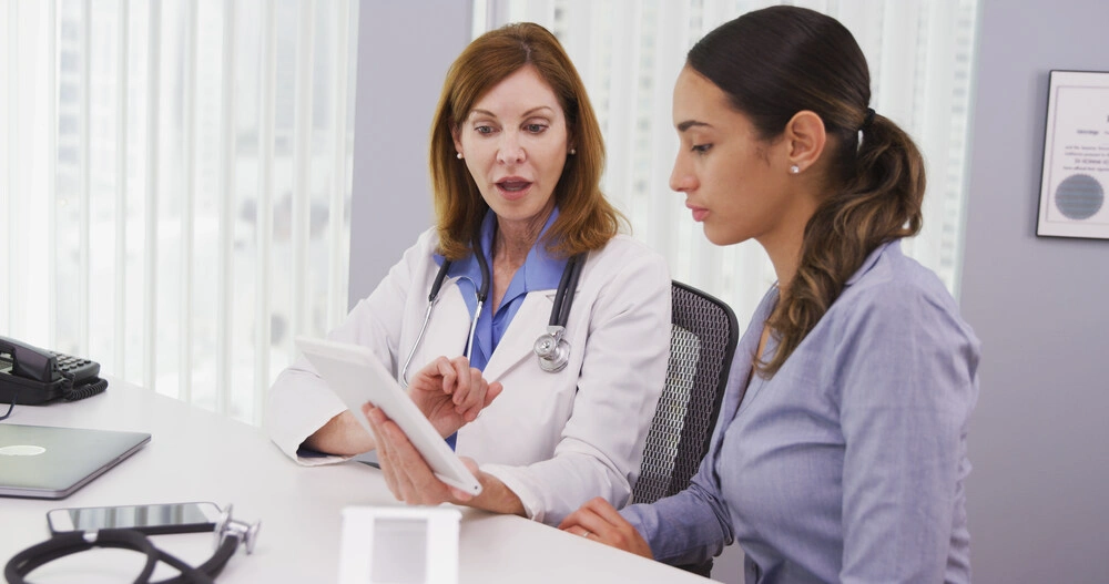 Senior doctor using tablet to share results of patients health condition