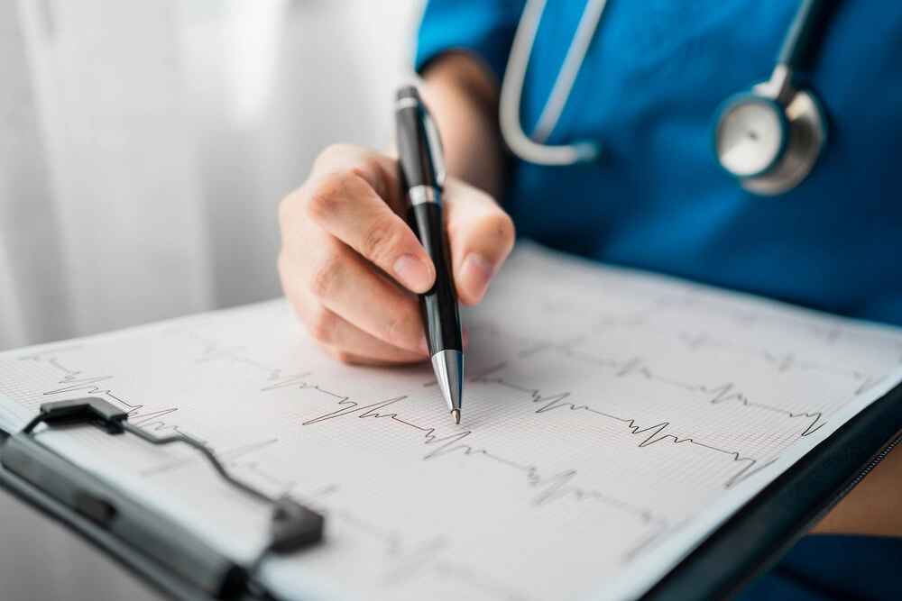 Close up of professional doctor reading and recording cardio diagram graph reports of a patient