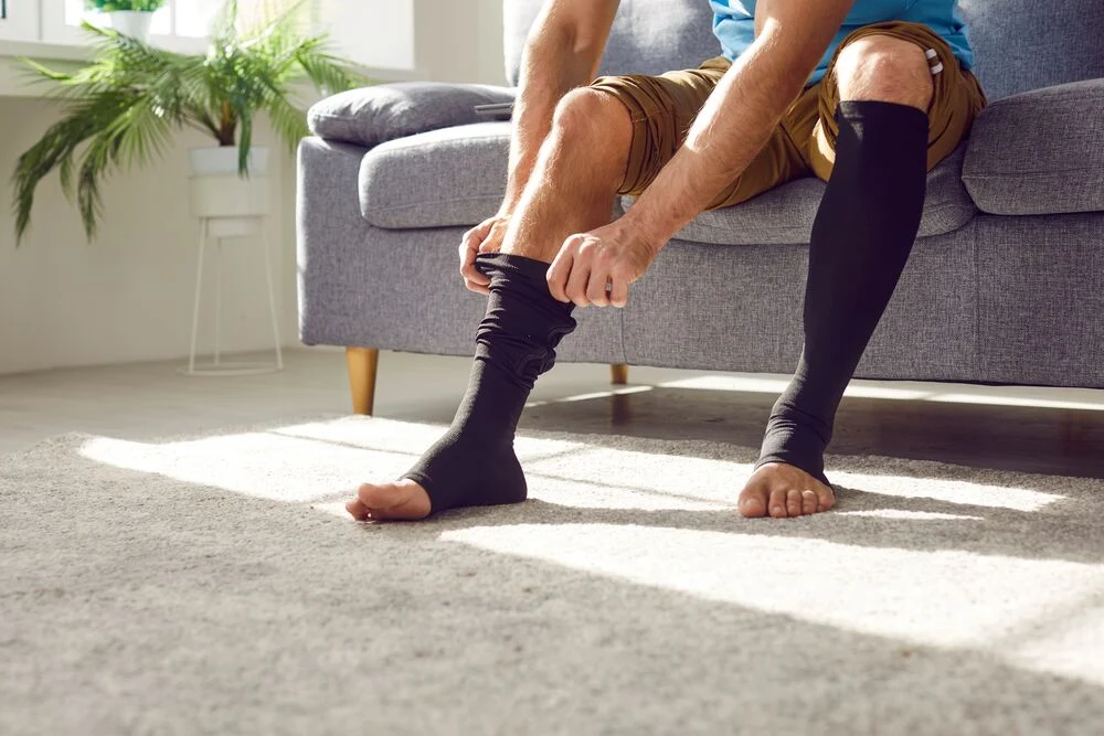 Man wears compression stockings due to varicose or recovery after thrombosis