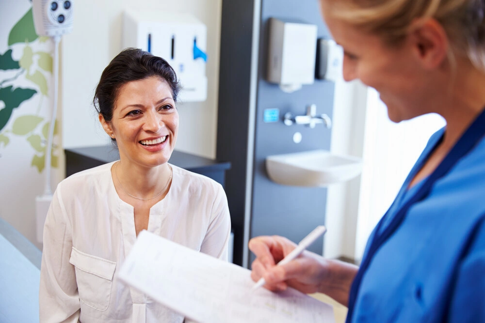 Female Patient And Doctor Have Consultation In Hospital Room