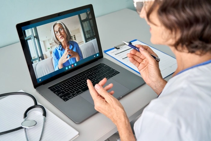 Female doctor therapist consulting older senior patient via virtual video call visit using laptop computer.